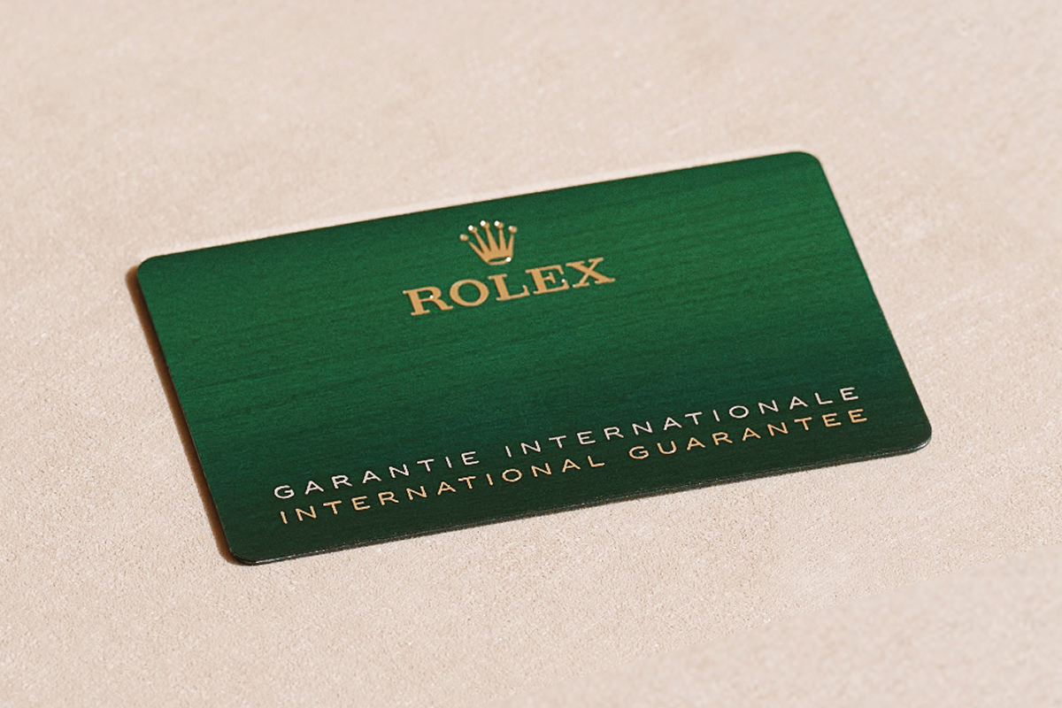 A green Rolex international guarantee card sits inside of a green leather holder